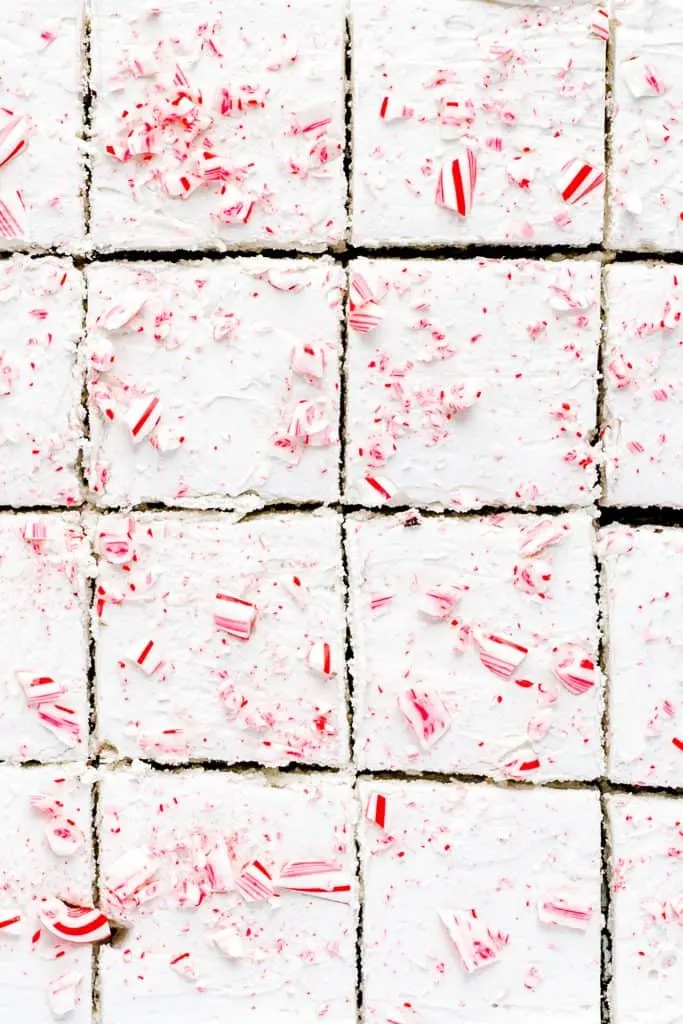 close up overhead shot of sliced gluten free peppermint brownies with white chocolate peppermint buttercream and crushed candy canes