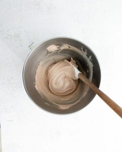 overhead shot of dark chocolate meringue cookie batter in a silver bowl with a spatula