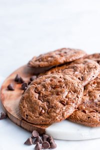 Flourless Chocolate Cookies arranged on a marble and wood board garnished with chocolate chips