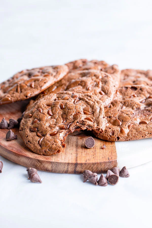 flourless chocolate cookies on a wood and marble board garnished with chocolate chips