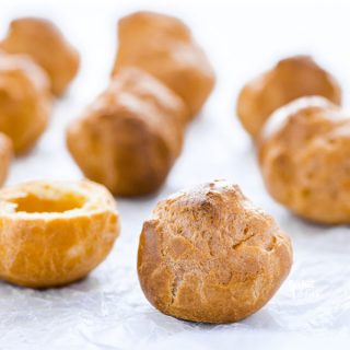 round gluten free choux pastry shells on a marble board covered in wax paper