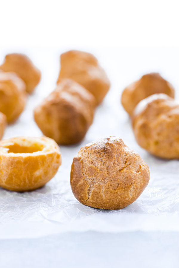 round gluten free choux pastry shells on a marble board covered in wax paper