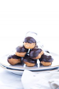 Classic Gluten Free Chocolate Eclair Recipe ready to serve on a stack of gold rimmed white plates