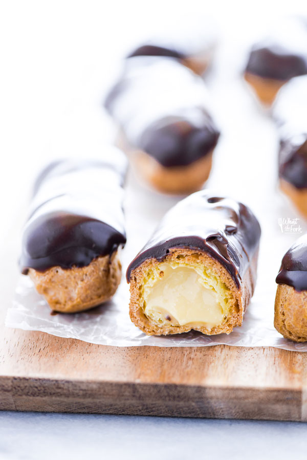 a chocolate eclair cut in half to show the pastry cream in the center