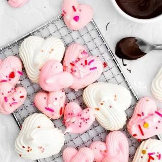 overhead shot of a finished heart meringue cookie recipe with pink and white heart meringues topped with Valentine's Day sprinkles