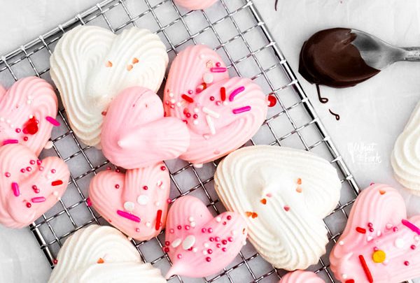 overhead shot of a finished heart meringue cookie recipe with pink and white heart meringues topped with Valentine's Day sprinkles