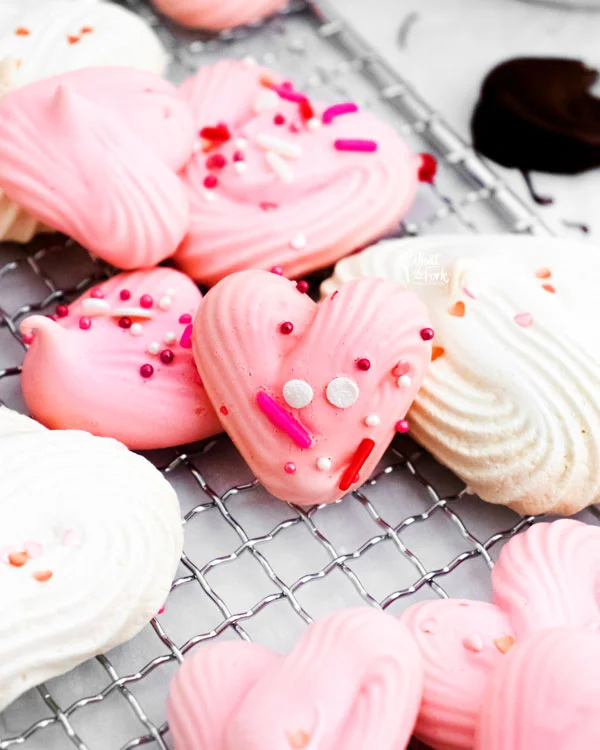 baked heart meringue cookie recipe with pink and white heart meringues topped with pink and white sprinkles
