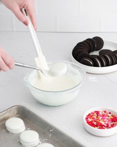 an Oreo being dipped in white chocolate