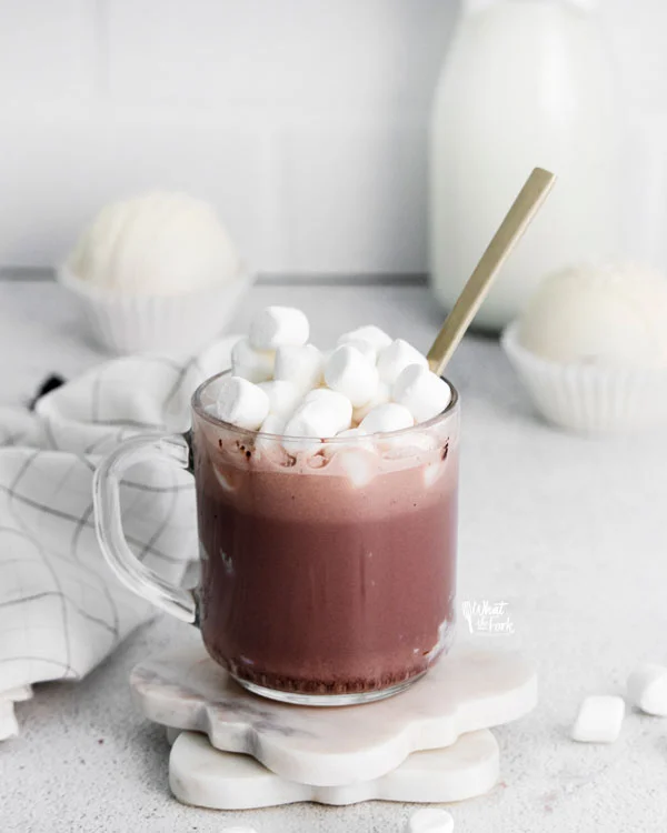 hot cocoa in a clear glass mug topped with mini marshmallows