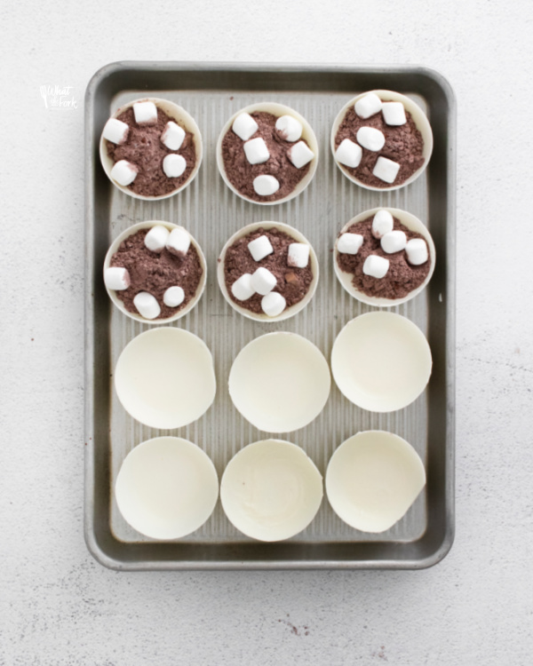 white hot chocolate bombs on a baking sheet being assembled