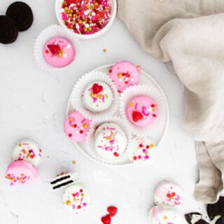 overheard shot of Valentine's Chocolate Covered Oreos on a white plate and scattered on a white surface