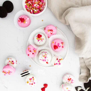 overheard shot of Valentine's Chocolate Covered Oreos on a white plate and scattered on a white surface