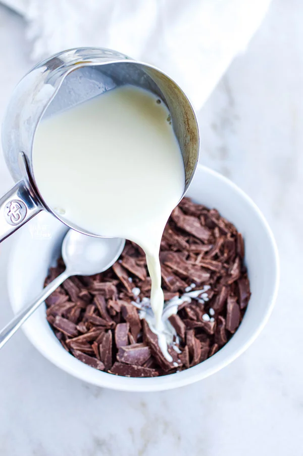 chocolate ganache recipe being made with the hot cream being poured over the chopped chocolate