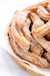 gluten free churros on a wood platter lined with wax paper