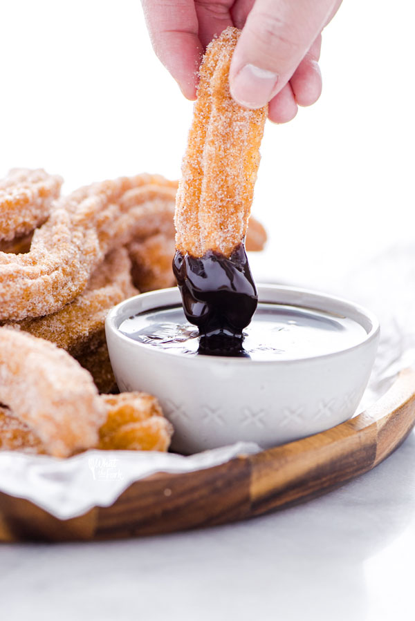 a gluten free churro being dipped into chocolate sauce