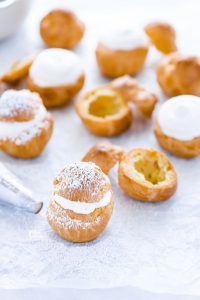 gluten free cream puffs on wax paper being filled with whipped cream