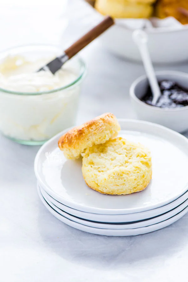 a gluten free scone on a stack of white plates that's been split in half