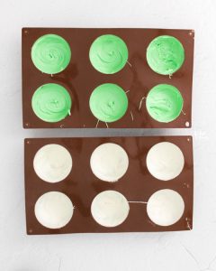 green and white chocolate in round molds to make St. Patrick's Day Hot Cocoa Bombs