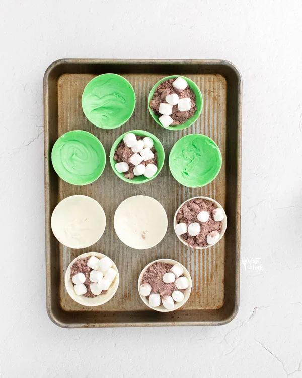 St. Patrick's Day Hot Cocoa Bombs on a metal sheet pan being assembled