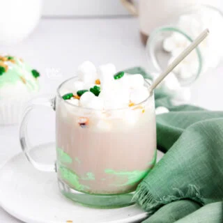 hot cocoa in a clear glass mug made with a St. Patrick's Day hot chocolate bomb