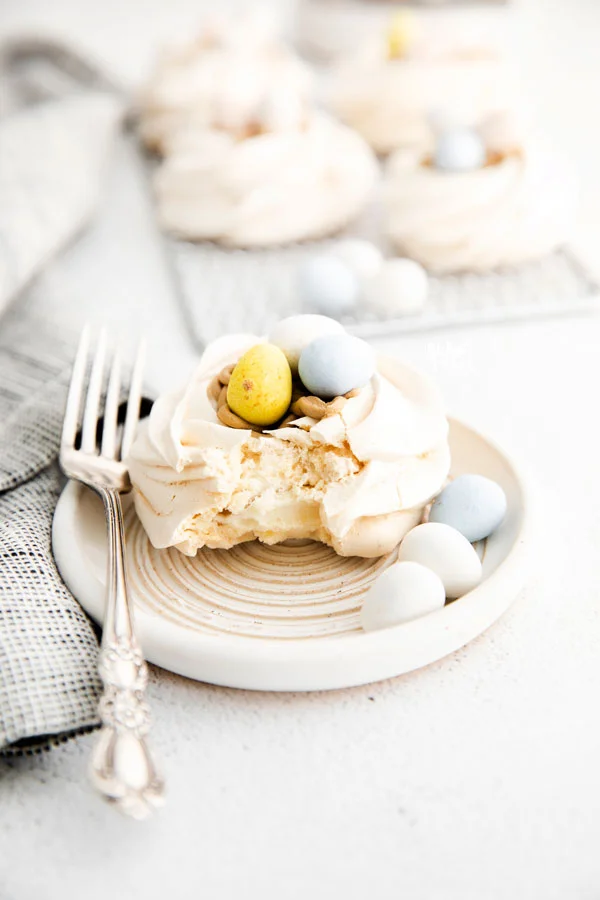 an Easter Meringue Nest on a small white plate with a bite taken out