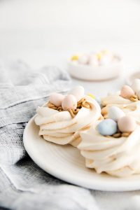 Easter Meringue Nests on a white plate with Mini Cadbury Eggs on top and in the background