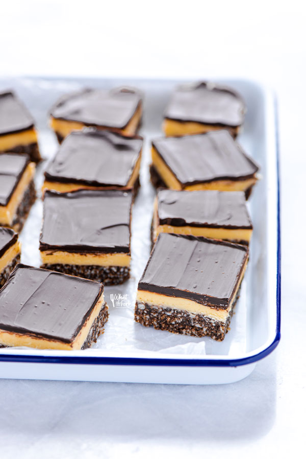 sliced Gluten Free Nanaimo Bars on a wax paper lined white and blue enamel tray