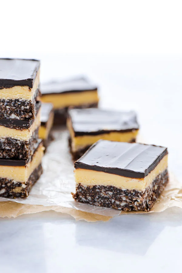 sliced Gluten Free Nanaimo Bars on wax paper lined parchment paper