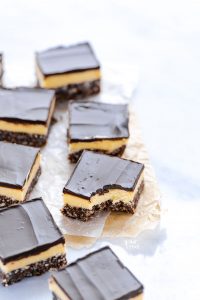 sliced Gluten Free Nanaimo Bars on parchment paper, one with a bite taken out