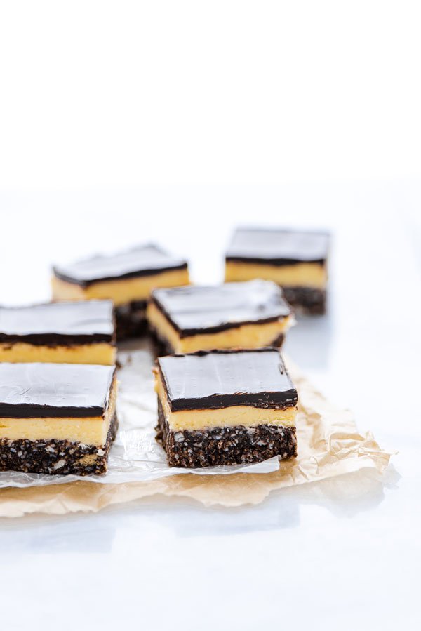 sliced Gluten Free Nanaimo Bars on top of brown parchment paper and wax paper