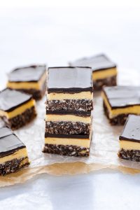 sliced and stacked Gluten Free Nanaimo Bars on parchment