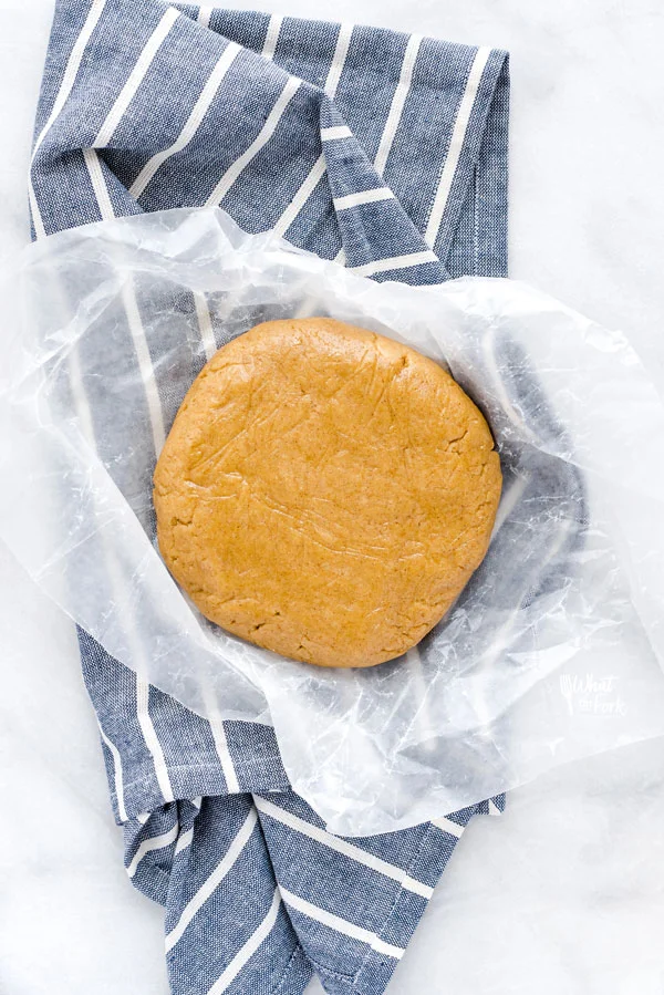 gluten free graham cracker dough in wax paper on a blue and white striped kitchen towel