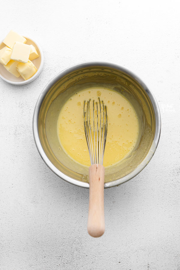 overhead shot of a lemon curd recipe being cooked with a whisk in the bowl