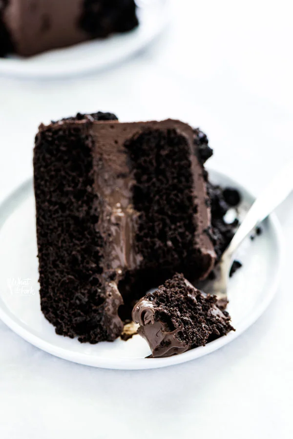 a slice of Gluten Free Brooklyn Blackout Cake on a white plate with a piece on a fork