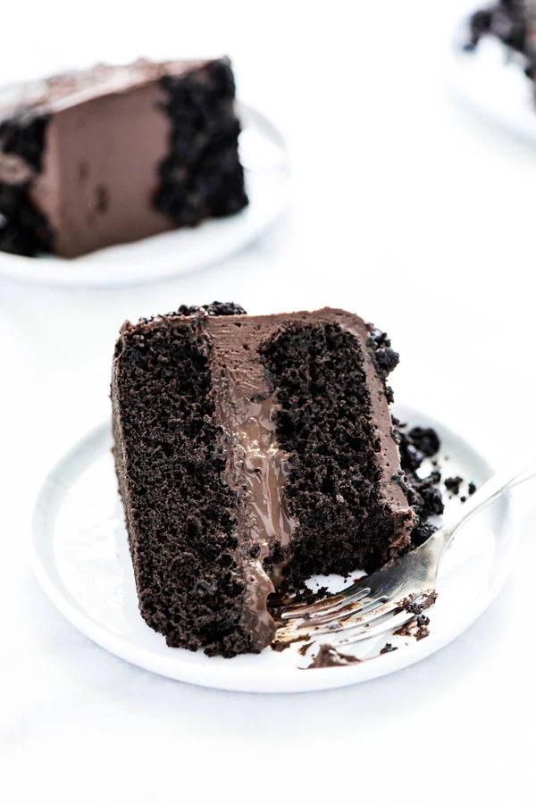 a piece of Gluten Free Brooklyn Blackout Cake on a white plate with a bite taken out