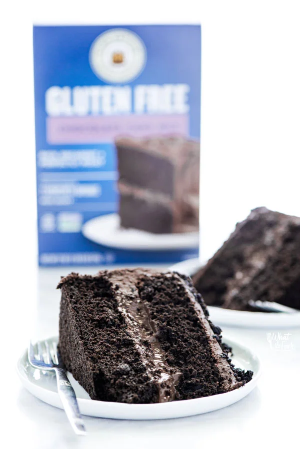 slices of Gluten Free Brooklyn Blackout Cake on white plates with a box of King Arthur Baking Company Gluten Free Chocolate Cake Mix in the background