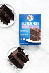 overhead shot of slices of Gluten Free Brooklyn Blackout Cake on white plates around a box of King Arthur Baking Company Gluten Free Chocolate Cake Mix