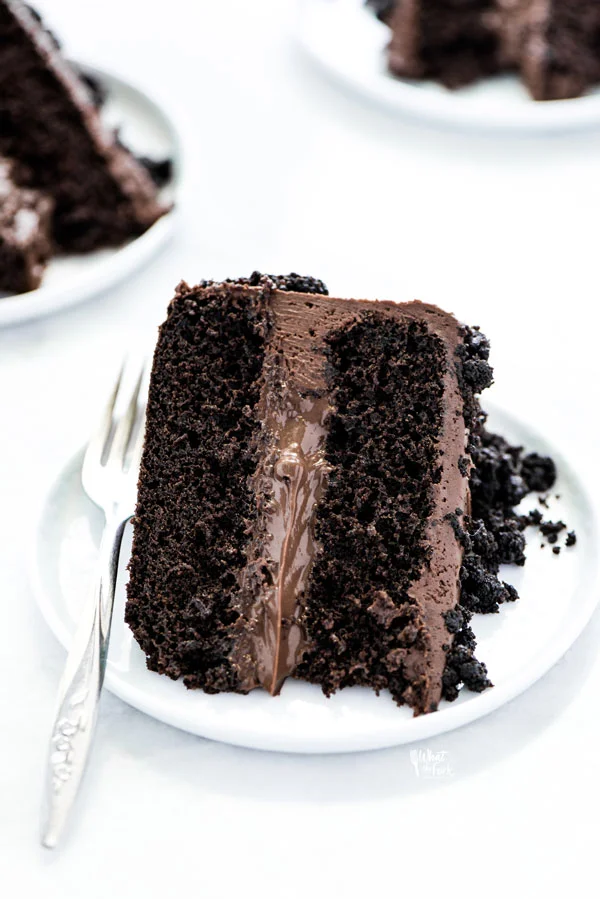 a slice of Gluten Free Brooklyn Blackout Cake on a white plate with a vintage silver fork