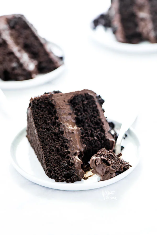 a slice of Gluten Free Brooklyn Blackout Cake on a white plate with a small bite on a silver fork