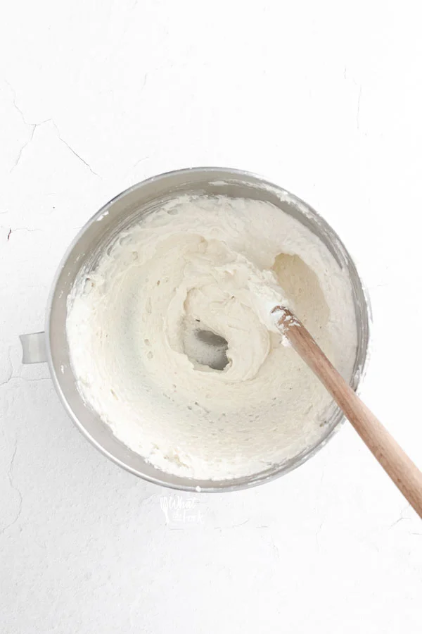 French Macaron batter in a silver mixing bowl with a wood handled spatula