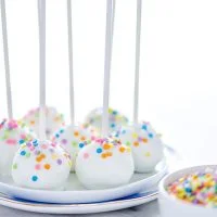 finished gluten free confetti cake pop recipe with cake pops on a stack of white plates ready to be served