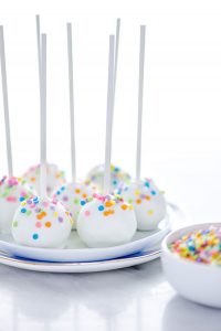 finished gluten free confetti cake pop recipe with cake pops on a stack of white plates ready to be served