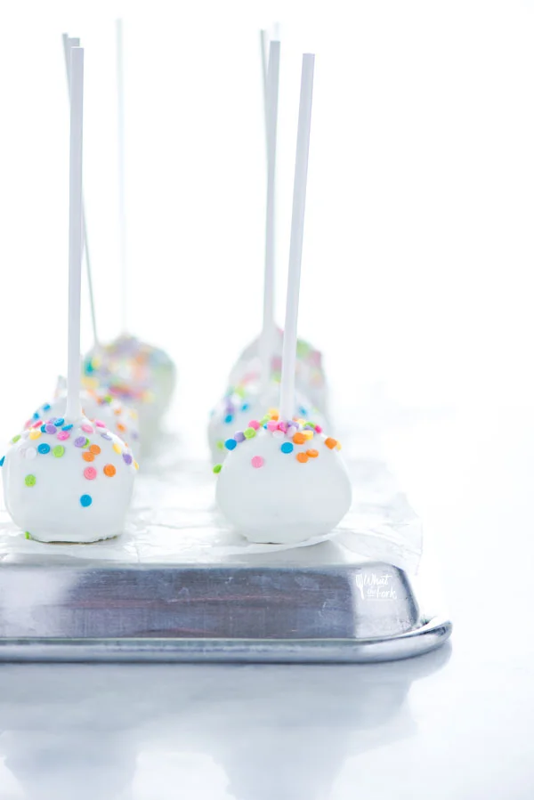 gluten free confetti cake pops on a over turned quarter sheet pan lined with wax paper