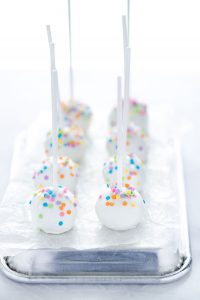 finished Gluten Free Confetti Cake Pop Recipe with 8 cake pops being served on top of an over-turned quarter sheet pan lined with wax paper