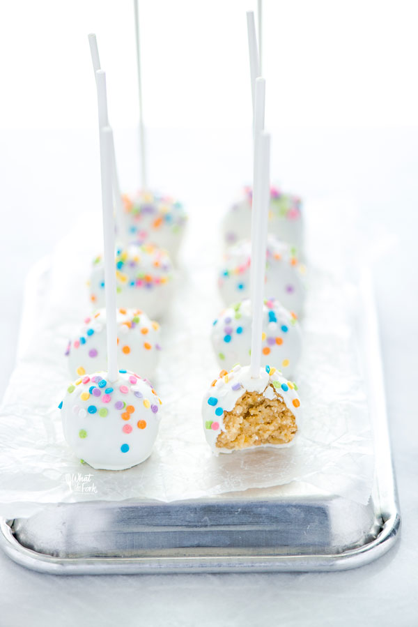 confetti cake pops on a serving tray, one with a bite taken out