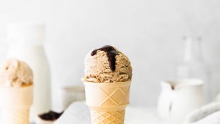 a scoop of No Churn Coffee Ice Cream Recipe served in a cake cone topped with a drizzle of chocolate sauce