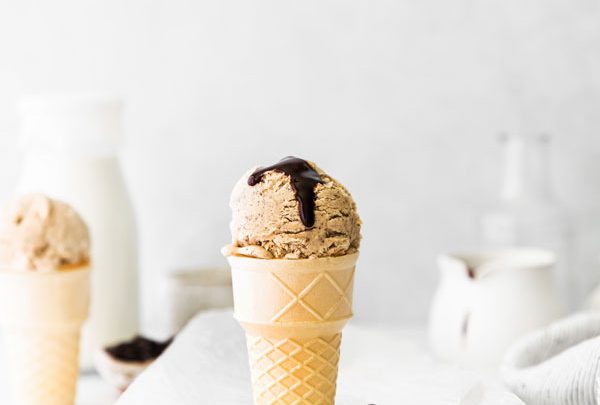 a scoop of No Churn Coffee Ice Cream Recipe served in a cake cone topped with a drizzle of chocolate sauce
