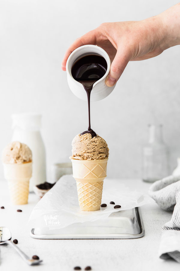 No Churn Coffee Ice Cream in an ice cream cone with chocolate sauce being poured on top