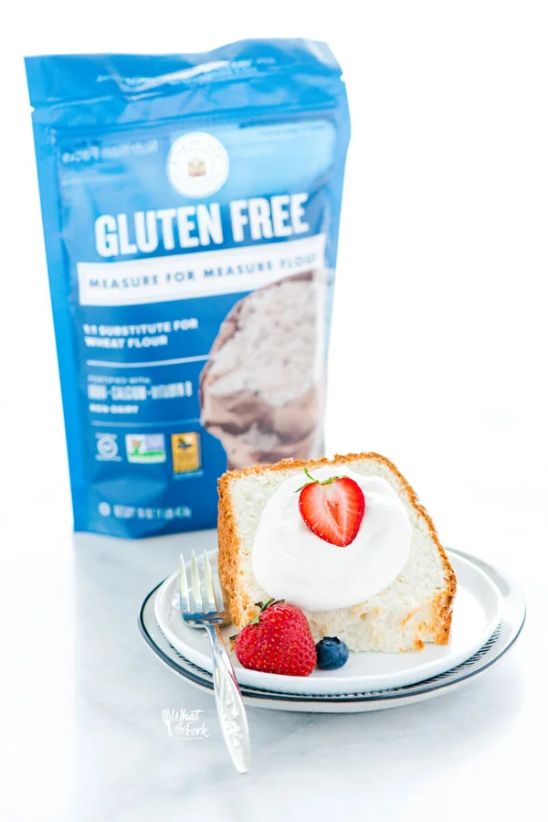 a slice of gluten free angel food cake on a plate with a bag of King Arthur Gluten Free Measure for Measure Flour in the background
