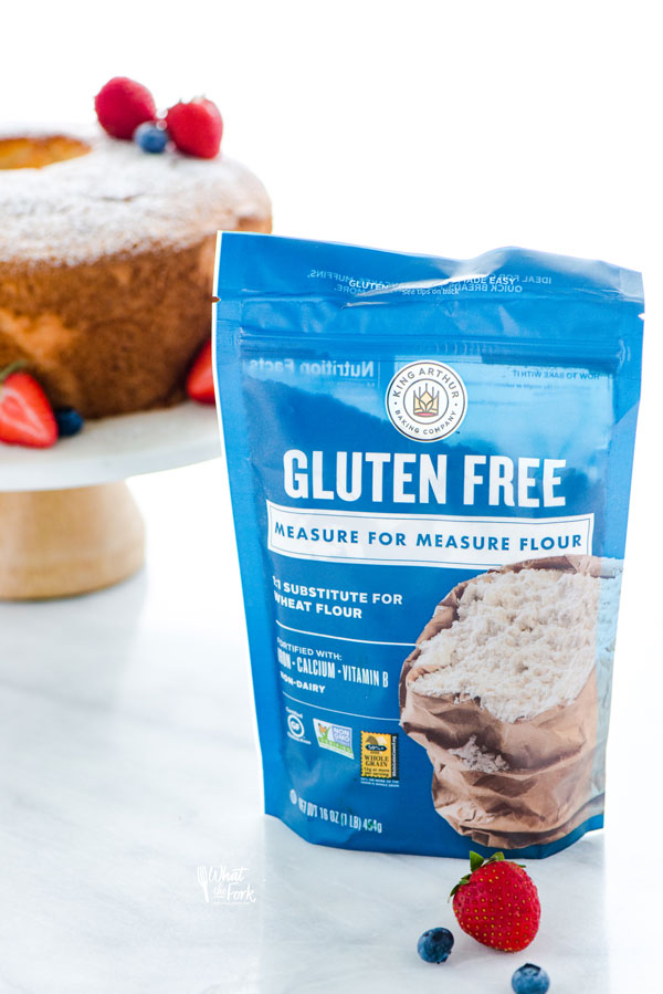 a bag of King Arthur Gluten Free Measure for Measure Flour with a gluten free angel food cake on a cake stand in the background